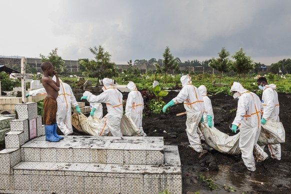 epa11874969 A child standing on a grave watches as members of the Congolese Red Cross and volunteers carry victims of the recent conflict in a cemetery in Goma, Democratic Republic of the Congo, 04 Fe ...