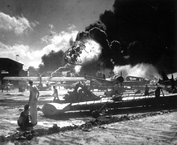 ** FOR USE AS DESIRED ** ** In this Dec. 7, 1941 photo released by the U.S. Navy, sailors stand among wrecked airplanes at Ford Island Naval Air Station as they watch the explosion of the USS Shaw in ...