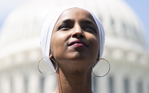 epa07670826 Democratic Representative from Minnesota Ilhan Omar listens to Independent Senator from Vermont Bernie Sanders (not pictured) speak to journalists about his plan to eliminate all $1.6 tril ...