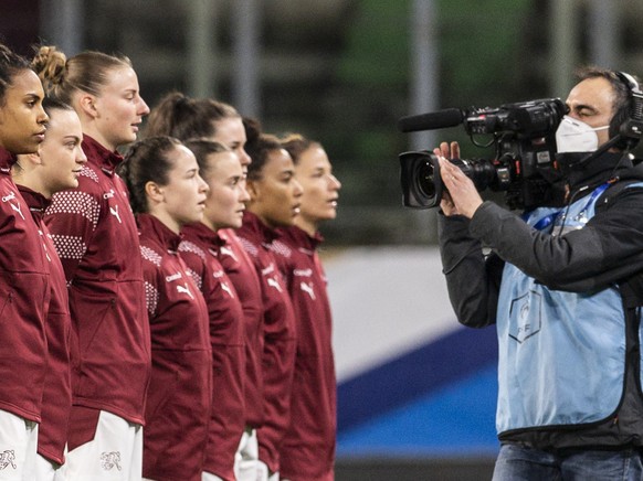 The Swiss team, right, stands for the national anthem next to the referees and the french team, left, ahead of the women
