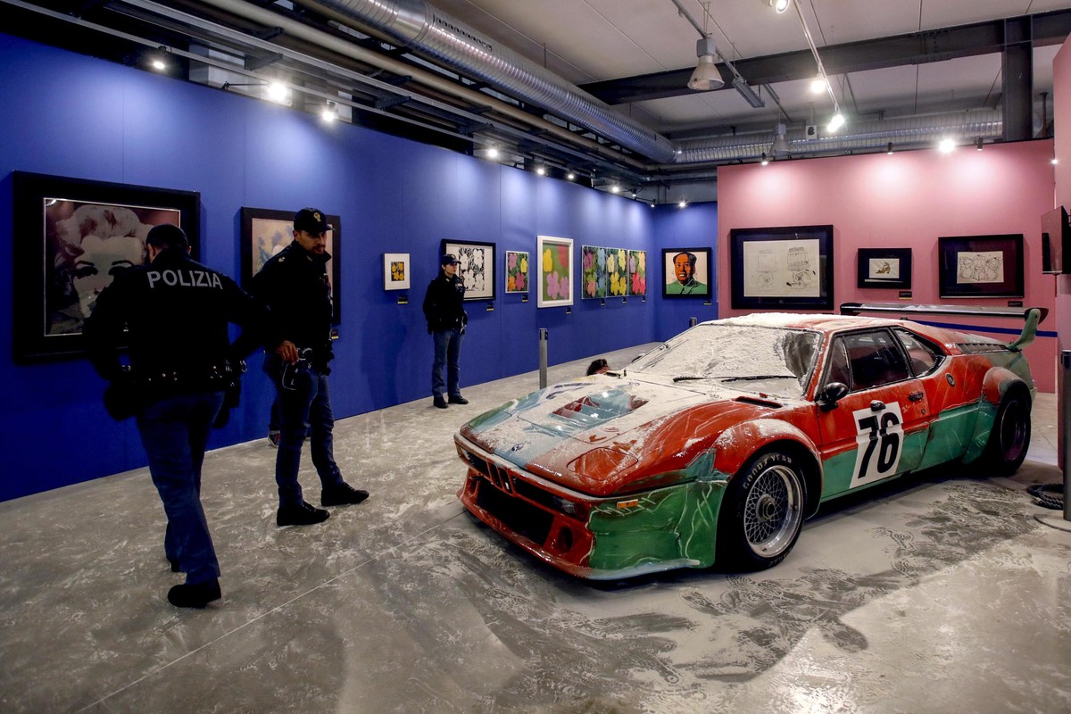 epa10312565 Police officers stand next to the 76 BMW M1 Procar painted by US artist Andy Warhol covered with flour, at the 'Andy Warhol: La Pubblicita Della Forma' exhibition at the Fabbrica ...