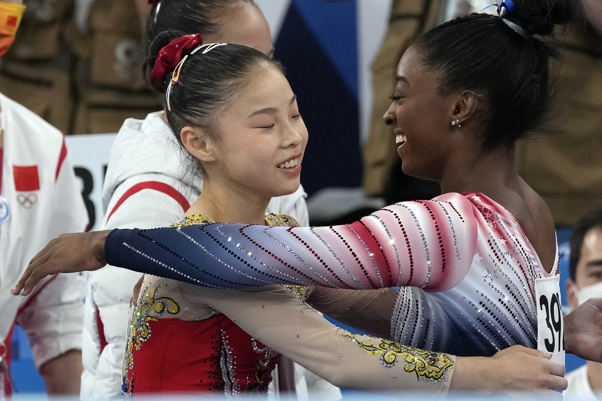 Gold medalist Guan Chenchen, of China, left, gets a hug from bronze medalist Simone Biles, of the United States, after performing on the balance beam during the artistic gymnastics women's appara ...