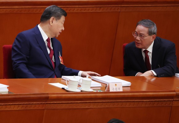 epa12795884 Chinese President Xi Jinping (L) speaks with Premier Li Qiang during the opening ceremony of the Fourth Session of the 14th National People's Congress of China at the Great Hall of th ...
