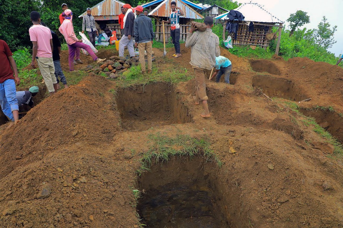 epa11494087 Relatives of the victims of a landslide dig graves near the accident site in the Kencho Sacha Gozdi district, Gofa Zone, southern Ethiopia, 24 July 2024. The number of victims reached at l ...