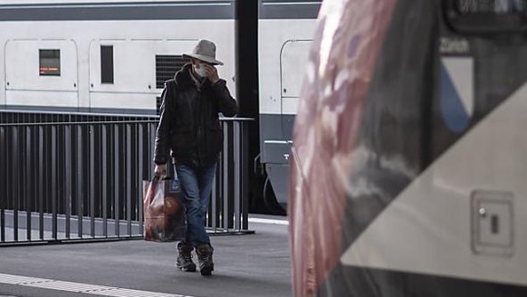 Ein Mann mit Maske auf dem Weg zum Zug am Bahnhof in St. Gallen. (Archivbild)