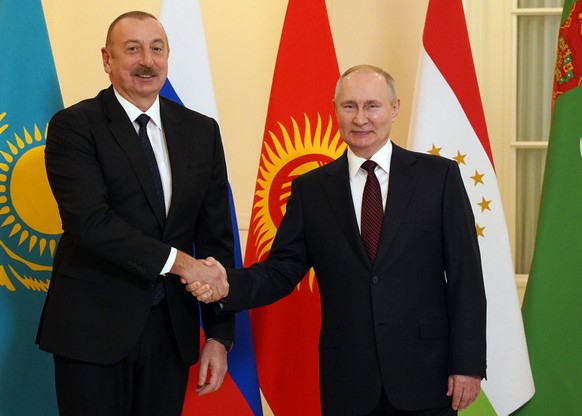 epa10378665 Russian President Vladimir Putin (R) and Azerbaijani President Ilham Aliyev shake hands ahead of an informal summit of the Commonwealth of Independent States (CIS) in St. Petersburg, Russi ...