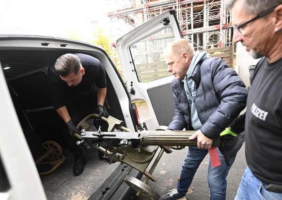 29.10.2025, Nordrhein-Westfalen, Remscheid: Polizisten transportieren ein Maschinengewehr als Teil der gefundenen Waffen ab. Die Ermittler sind in Remscheid auf einen weiteren versteckten Raum voller  ...