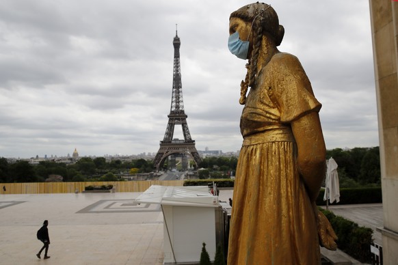 FILE- In this file photo dated Monday, May 4, 2020, a statue wears a mask along Trocadero square close to the Eiffel Tower in Paris. Britain will require all people arriving from France to isolate for ...