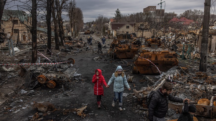 epa09874802 Vladyslava Liubarets (C), a Bucha resident, walks with her family past destroyed Russian military machinery, to meet her sister whom she did not see since the beginning of the Russian inva ...