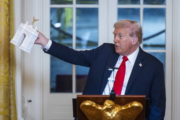 US President Donald Trump holds a model of the planned Triumph Arch as he speaks ahead of a dinner to raise money for his ballroom extension in the East Room of the White House in Washington, DC, on W ...