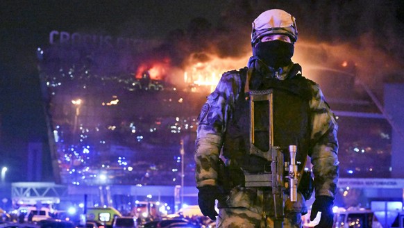 A Russian Rosguardia (National Guard) servicemen secures an area as a massive blaze seen over the Crocus City Hall on the western edge of Moscow, Russia, Friday, March 22, 2024. Several gunmen have bu ...
