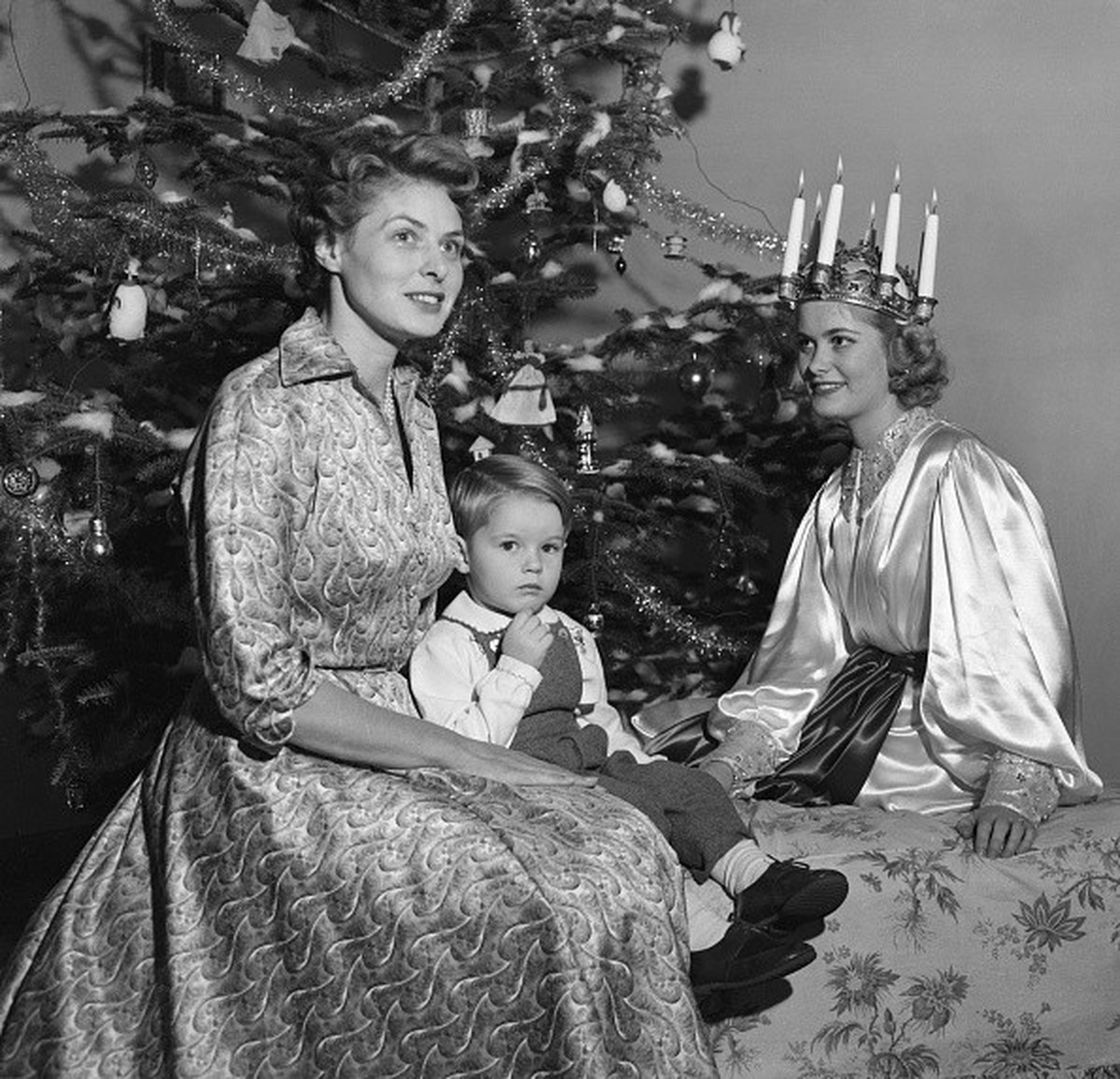 (Original Caption) Light Queen Visits Ingrid and Son. Rome: Sweden's "Light Queen," Kerstin Ornoe (right), complete with a crown and silk dress, shares the spotlight under a huge tree w ...