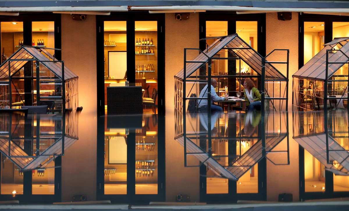 epa08431260 Guests sit at a table in a small greenhouse at the 'Novy's Brasserie' Restaurant in Hagen, Germany, 18 May 2020 (issued 19 May 2020). After nearly two months of shutdown due ...