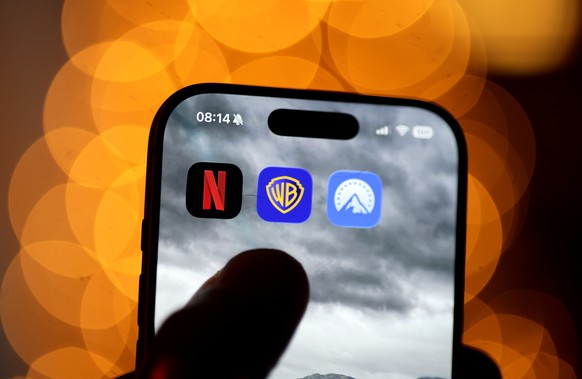 epa12579813 The app logos of Netflix, Warner Brothers and Paramount are seen on a smartphone display in Berlin, Germany, 09 December 2025. Following Netflix's 82 billion dollars offer, the next m ...
