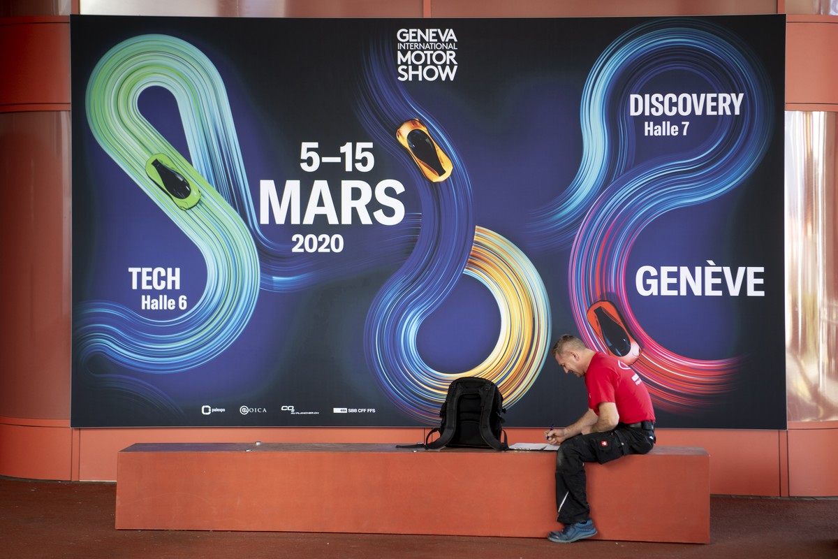 Un ouvrier photographie devant un panneau du Geneva International Motor Show, GIMS, (salon de l'automobile) ce lundi 24 fevrier 2020 a Palexpo a Geneve. (KEYSTONE/Laurent Gillieron)