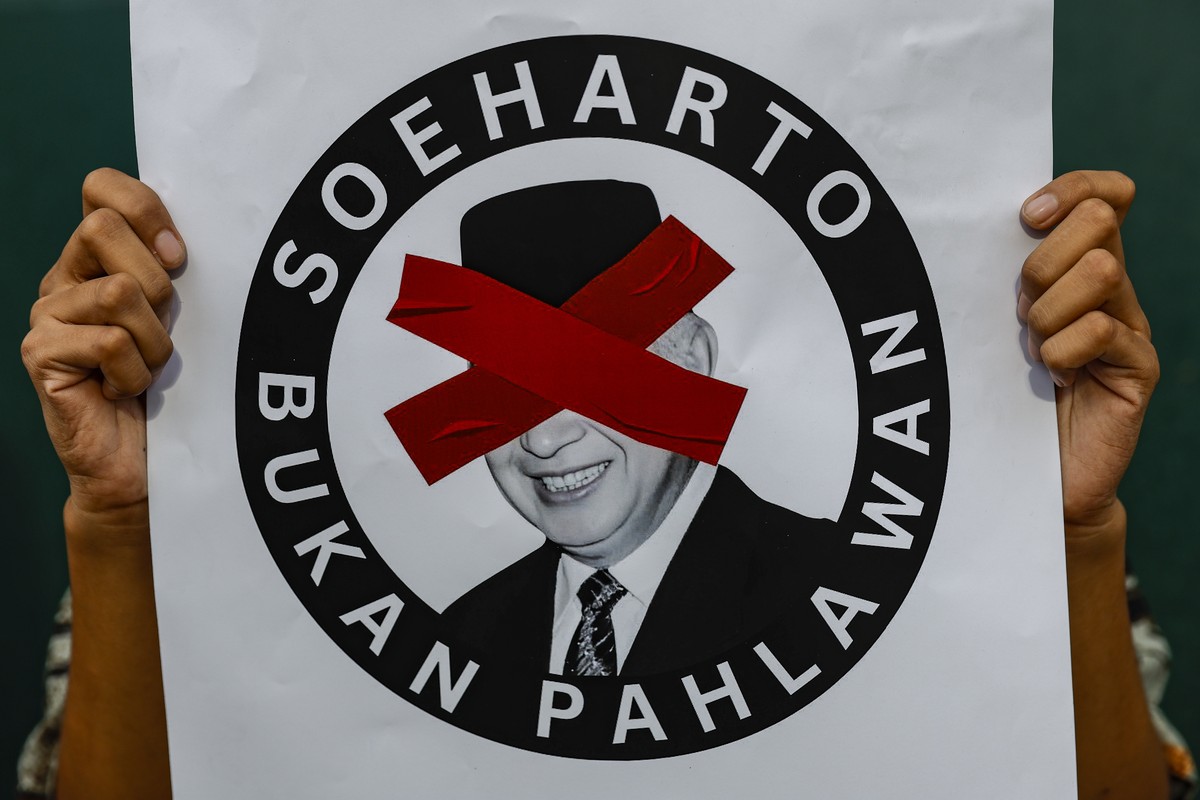epaselect epa12515776 A person holds a placard reading 'Suharto is not a hero' during a protest opposing the recognition of late President Suharto as a national hero in Jakarta, Indonesia, 1 ...