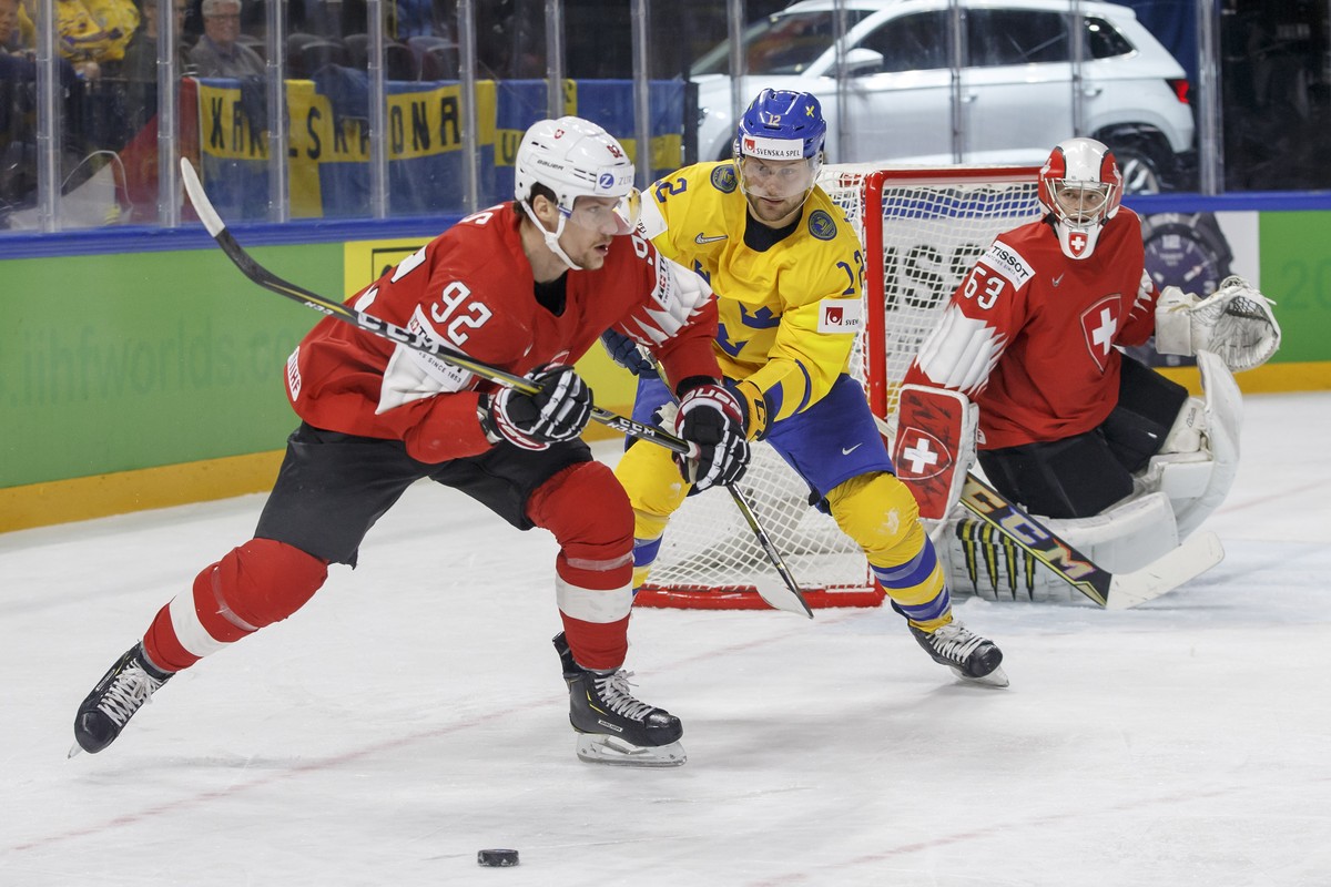 Switzerland's forward Gaetan Haas, left, vies for the puck with Sweden's forward Johan Larsson, center, past Switzerland's goaltender Leonardo Genoni, right, during the IIHF 2018 World  ...