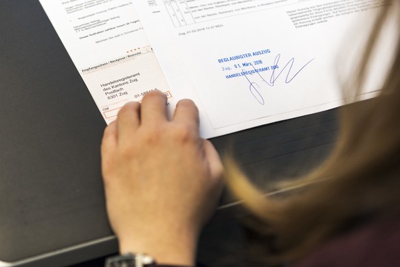 An employee certifies a trade register excerpt with a stamp and her signature at the counter of the Zug Commercial Registry, pictured in Zug, Switzerland, on March 1, 2018. The Commercial Registry is  ...