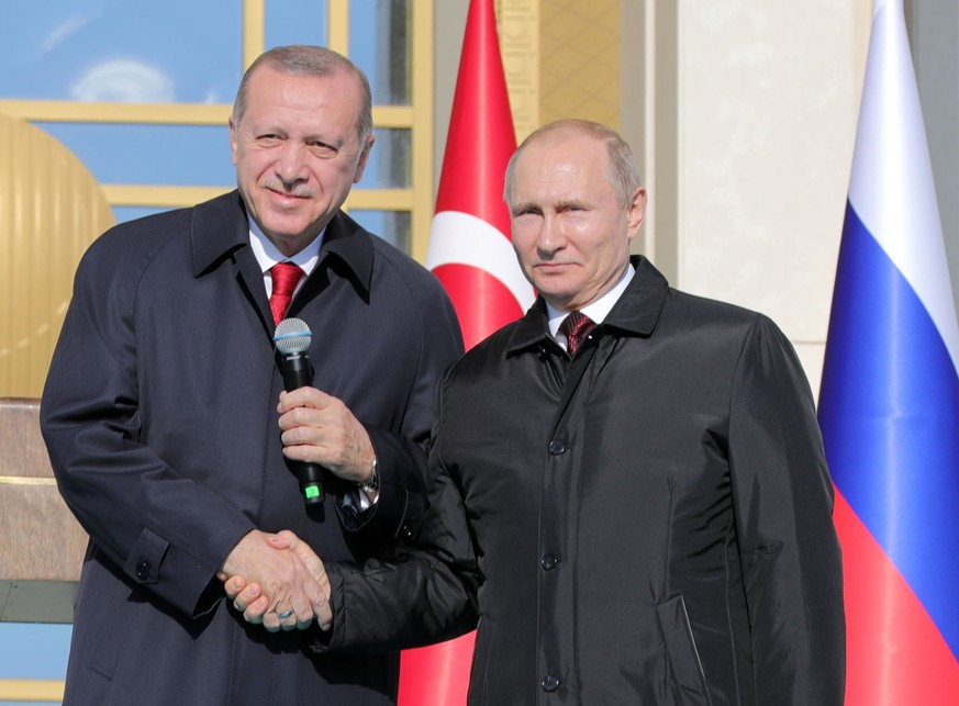 epa06643530 Russian President Vladimir Putin (R) and Turkish President Recep Tayyip Erdogan (L) shake hands during a symbolic ground-breaking ceremony for Akkuyu Nuclear Power Plant via video link, at ...