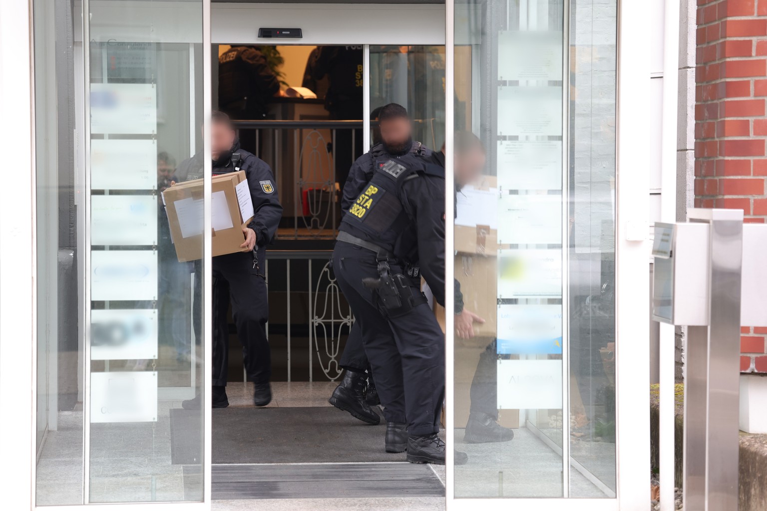 17.04.2024, Solingen: Polizeibeamte tragen in Kartons sichergestelltes Material aus einem Geb