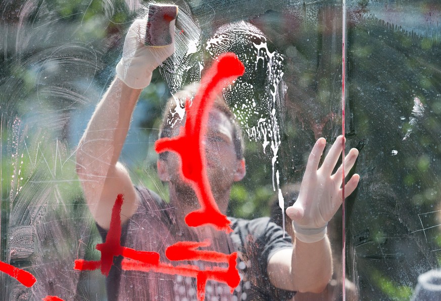 epaselect epa06077771 A resident of the 'Schanzenviertel' district cleans the window of a bus stop smeared in clashes during the recent G20 summit in Hamburg, northern Germany, 09 July 2017. The G20 S ...