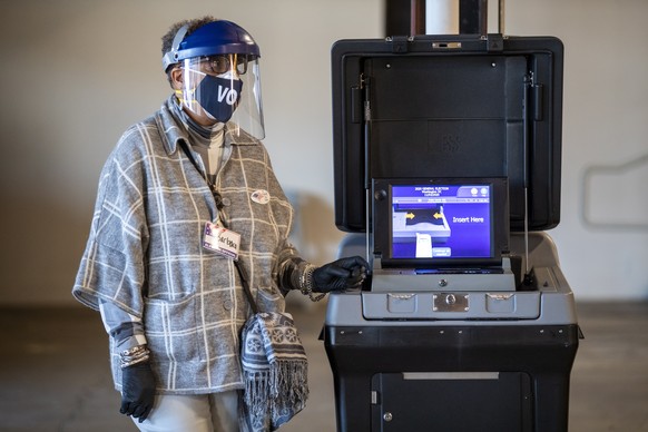 epa08795378 A poll worker waits to scan completed ballots at the Union Market polling station in Washington, DC, USA, 03 November 2020. Americans vote on Election Day to choose between re-electing Don ...