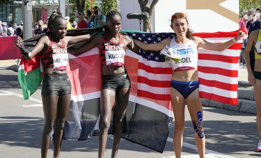 epa09402210 (L-R) Peres Jepchirchir of Kenya (gold), Brigid Kosgei of Kenya (silver) and Molly Seidel of the US (bronze) pose together after crossing the finish line during the Women&#039;s Marathon d ...