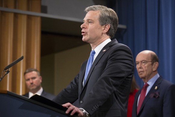epa07328398 Director of the Federal Bureau of Investigation (FBI) Christopher Wray (C) speaks beside US Secretary of Commerce Wilbur Ross (R) and other officials during a news conference held to annou ...
