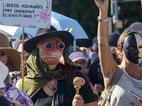 Eine Person (links) demonstrierte in Genf im Kostüm eines Pestdoktors. Die Schnabelmaske war im Mittelalter Teil der Arztausrüstung.