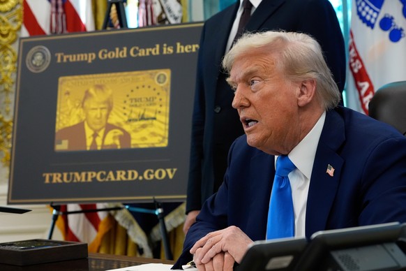 FILE - A poster showing the Trump Gold Card is seen as President Donald Trump signs executive orders in the Oval Office of the White House, Sept. 19, 2025, in Washington. (AP Photo/Alex Brandon, File) ...