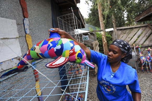 epa10228970 A Kenyan worker from the social enterprise &#039;Ocean sole&#039; arranges some art pieces made from recylcled flip-flops for drying at their workshop in Nairobi, Kenya, 06 October 2022 (i ...