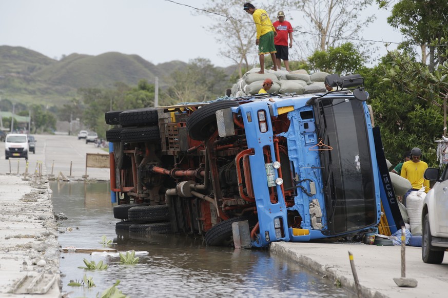 Workers transfer sacks of grains from a toppled truck that fell into an area where the road was being repaired following floodwaters in Cagayan province, northeastern Philippines on Sunday, Sept. 16,  ...