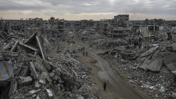 People walk amidst the destruction caused by the Israeli air and ground offensive in Rafah, southern Gaza Strip, Monday, Feb. 24, 2025. (AP Photo/Jehad Alshrafi)