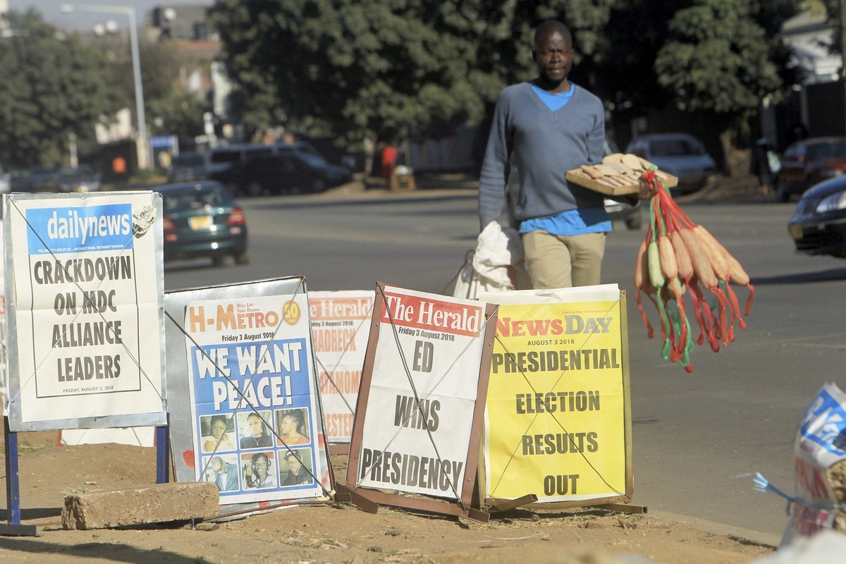A vendor sells sponges near newspaper headlines on the streets of Harare, Friday, Aug. 3, 2018. Zimbabwe's President Emmerson Mnangagwa won an election Friday with just over 50 percent of the bal ...