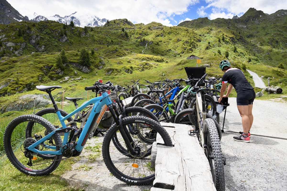 People taking a break and charging their E-Bike (Mountainbike) at the "Cabane Marcel Brunet" during a press tour of the "discovery trail", backdroped of mountains of the Swiss Alps ...