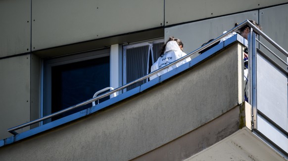 epa09846341 Two forensic police officers inspect the scene from the balcony of the building where four people were found dead and one seriously injured at the foot of a building after reportedly falli ...