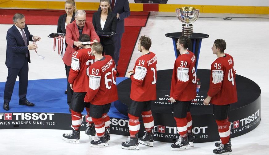 Swiss Defense and Sport Minister Guy Parmelin, 2nd left, next to Rene Fasel, left, President of IIHF, gives the silver medal to Switzerland&#039;s forward Kevin Fiala past #21 teammates forward Trista ...