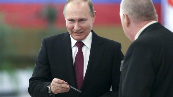 Russian President and Presidential candidate Vladimir Putin, center, prepares to cast his ballot during Russia&#039;s presidential election in Moscow, Russia, Sunday, March 18, 2018. Putin&#039;s vict ...