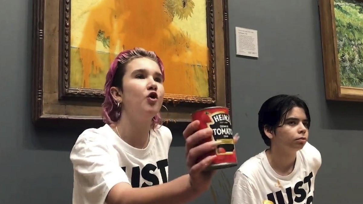 Handout photo issued by Just Stop Oil of two protesters who have thrown tinned soup at Vincent Van Gogh's famous 1888 work Sunflowers at the National Gallery in London, Friday Oct. 14, 2022. The  ...