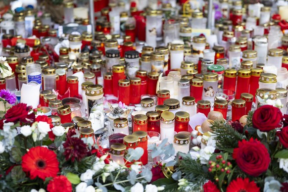 epa12648733 Flowers and candles are left in tribute to the victims after the fire at a bar in Crans-Montana, Switzerland, 14 January 2026. 40 people mostly teenagers lost their lives and 116 were seve ...