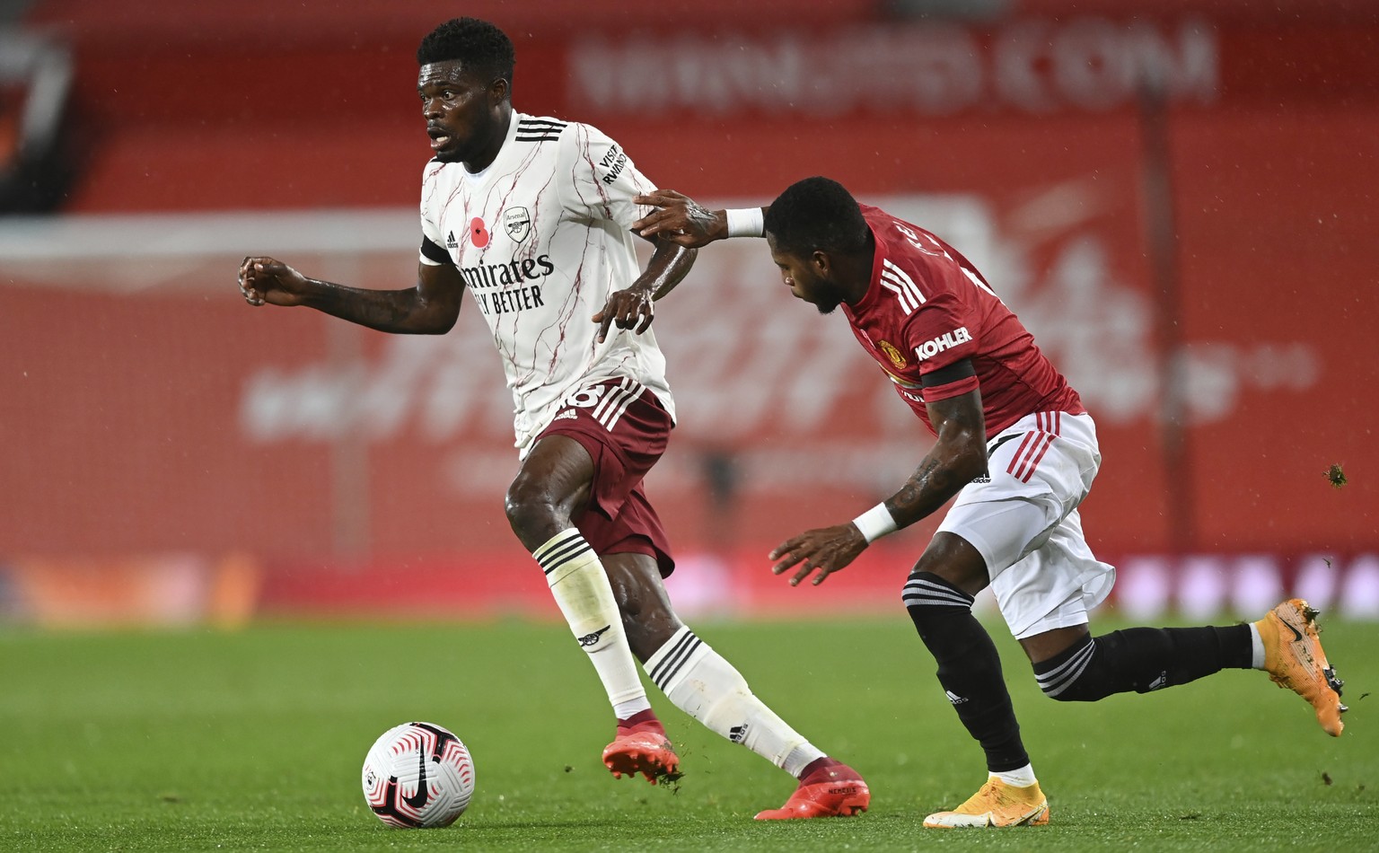 Arsenal&#039;s Thomas Partey, left, is challenged by Manchester United&#039;s Fred during the English Premier League soccer match between Manchester United and Arsenal at the Old Trafford stadium in M ...