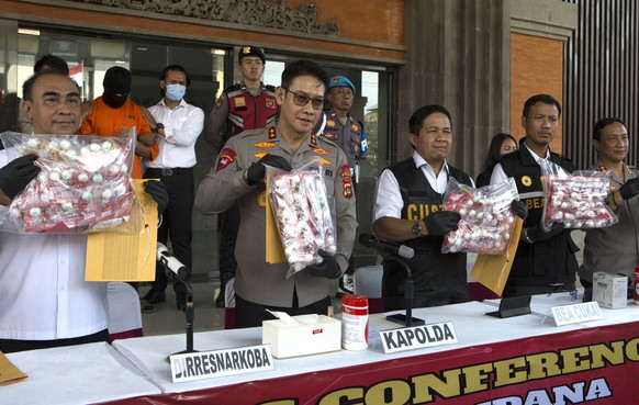 Authorities hold a news conference as an Australian man, second left in the background, arrested for allegedly smuggling cocaine stands at the police headquarters in Bali, Indonesia, Monday, May 26, 2 ...