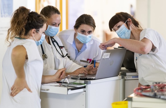 Aerztinnen und Pflegende besprichen sich in einem Huddle, der spezialisierten Kurzsitzung, ueber die anstehenden Patientenbesuche auf der Abteilung fuer COVID-Patienten im HFR Freiburg Kantonsspital,  ...