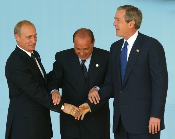 epa10686472 (FILE) Italian Prime Minister Silvio Berlusconi (C) pictured in a gesture to stop shaking hands of Russian President Vladimir Putin's (L) and US President George W. Bush's at the ...