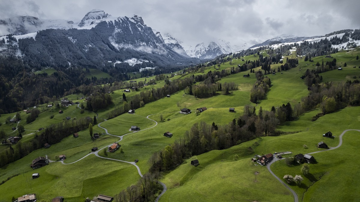 Bauernhoefe am Grabserberg mit Blick Richtung Wildhaus, darueber frisch verschneite Berge, aufgenommen am Donnerstag, 18. April 2024, in Grabs. (KEYSTONE/Gian Ehrenzeller)