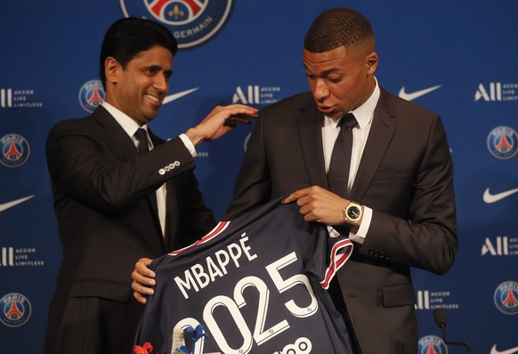 FILE -PSG striker Kylian Mbappe shows his jersey with PSG president Nasser Al-Khelaifi during a press conference,May 23, 2022 at the Paris des Princes stadium in Paris. (AP Photo/Michel Spingler, File ...