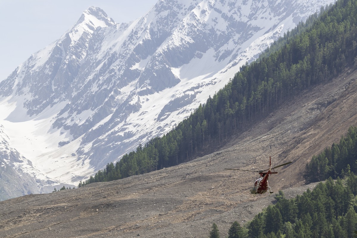 epa12148864 A helicopter flies over the landslide a few days after a massive avalanche, triggered by the collapse of the Birch Glacier, that swept down to the valley floor and demolishing the village  ...