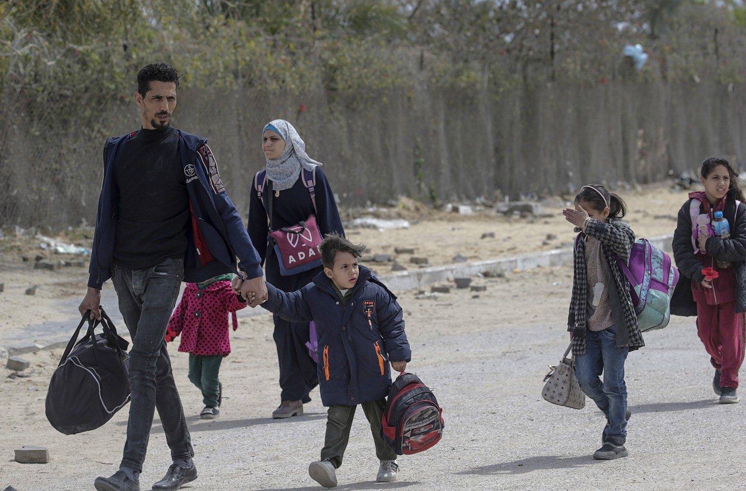 epa11241209 Internally displaced Palestinians, including children, carry their belongings as they walk at a street after the Israeli army asked residents of Khan Yunis town to leave their homes and he ...