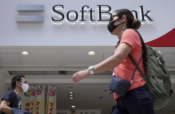 People walk by a SoftBank shop on Monday, Aug. 8, 2022, in Tokyo. Japanese technology company SoftBank Group sank into losses for the first fiscal quarter as the value of its investments declined amid ...