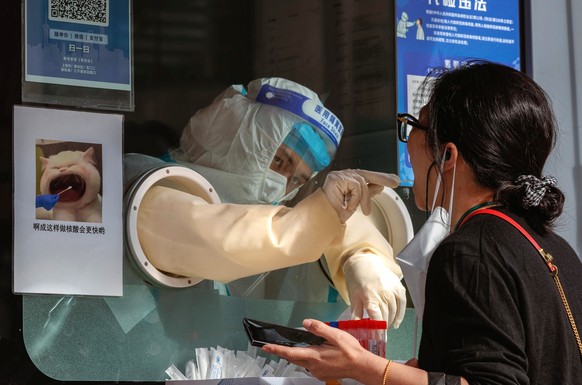 epa10270975 A woman takes a Coronavirus PCR test on the street testing booth, in Shanghai, China, 28 October 2022. According to the Shanghai Health Commission report on 28 October, Shanghai city repor ...